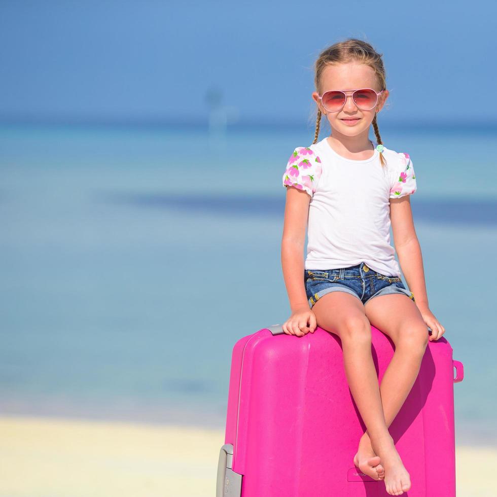 Girl sitting on pink luggage photo
