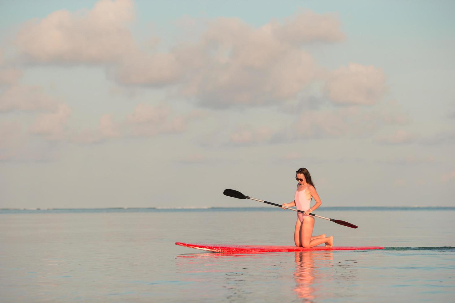 mujer en una tabla de remo al atardecer foto