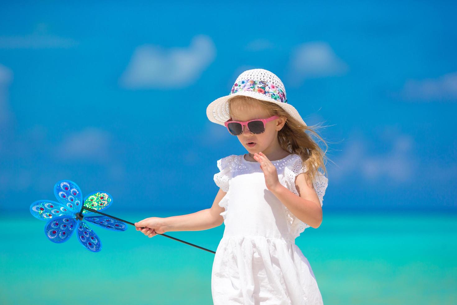 Chica con sombrero sosteniendo un molinillo en la playa foto