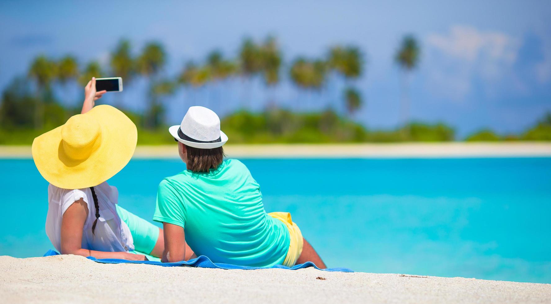 pareja tomando un selfie mientras está acostado en una playa foto