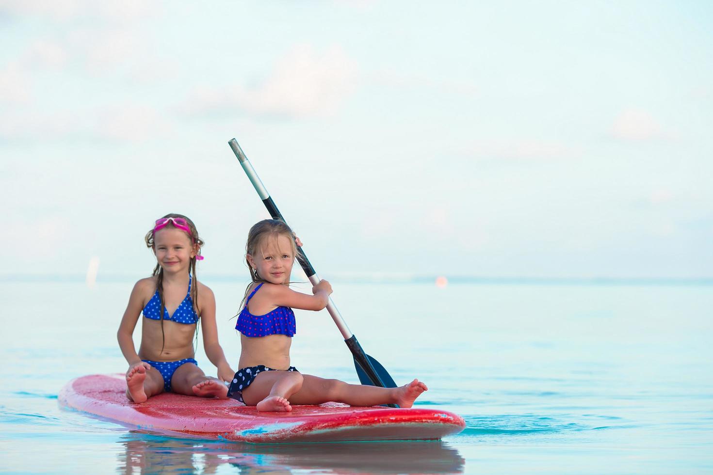 Two girls having fun paddleboarding photo