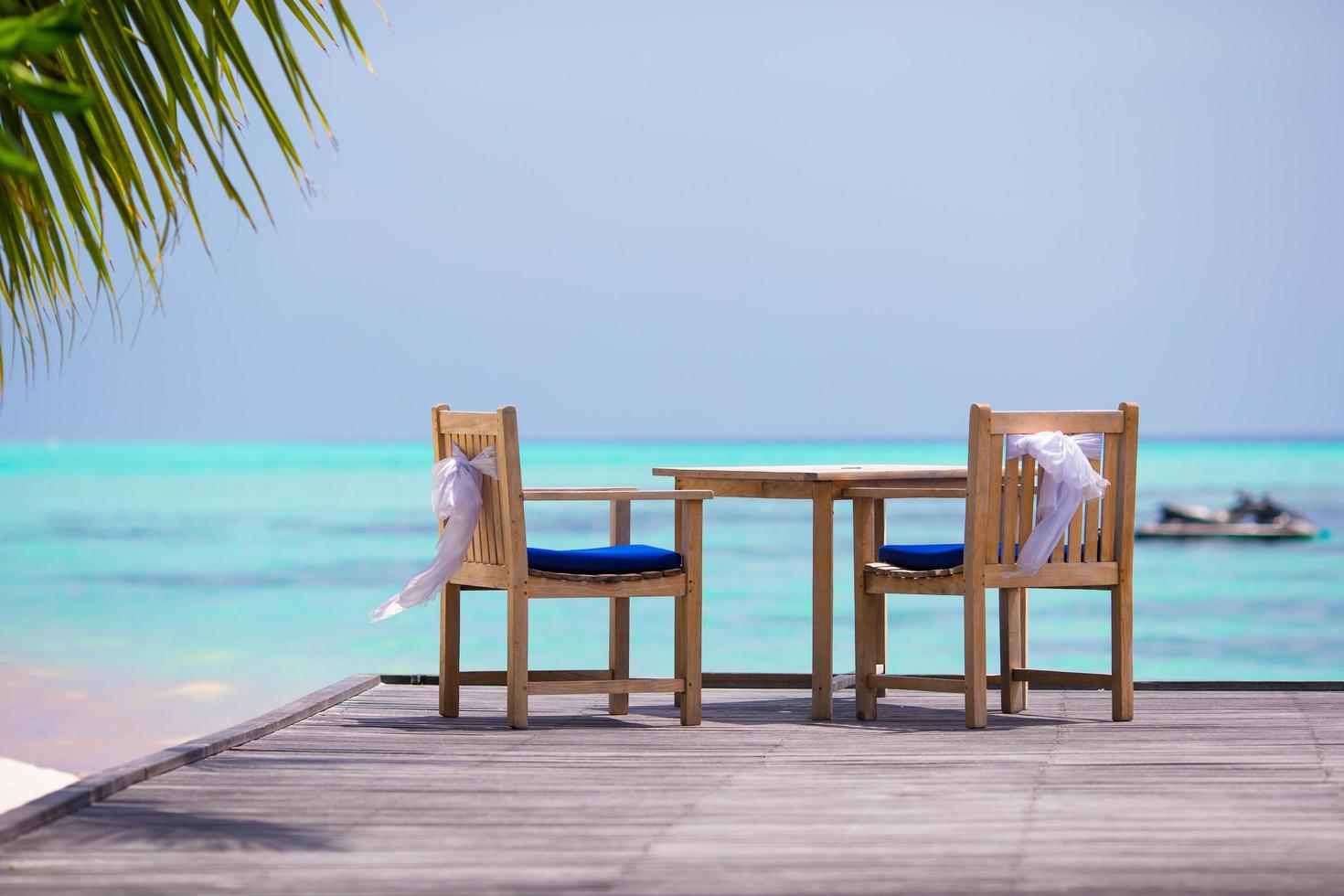 Wedding chairs decorated with white bows at outdoor cafe photo