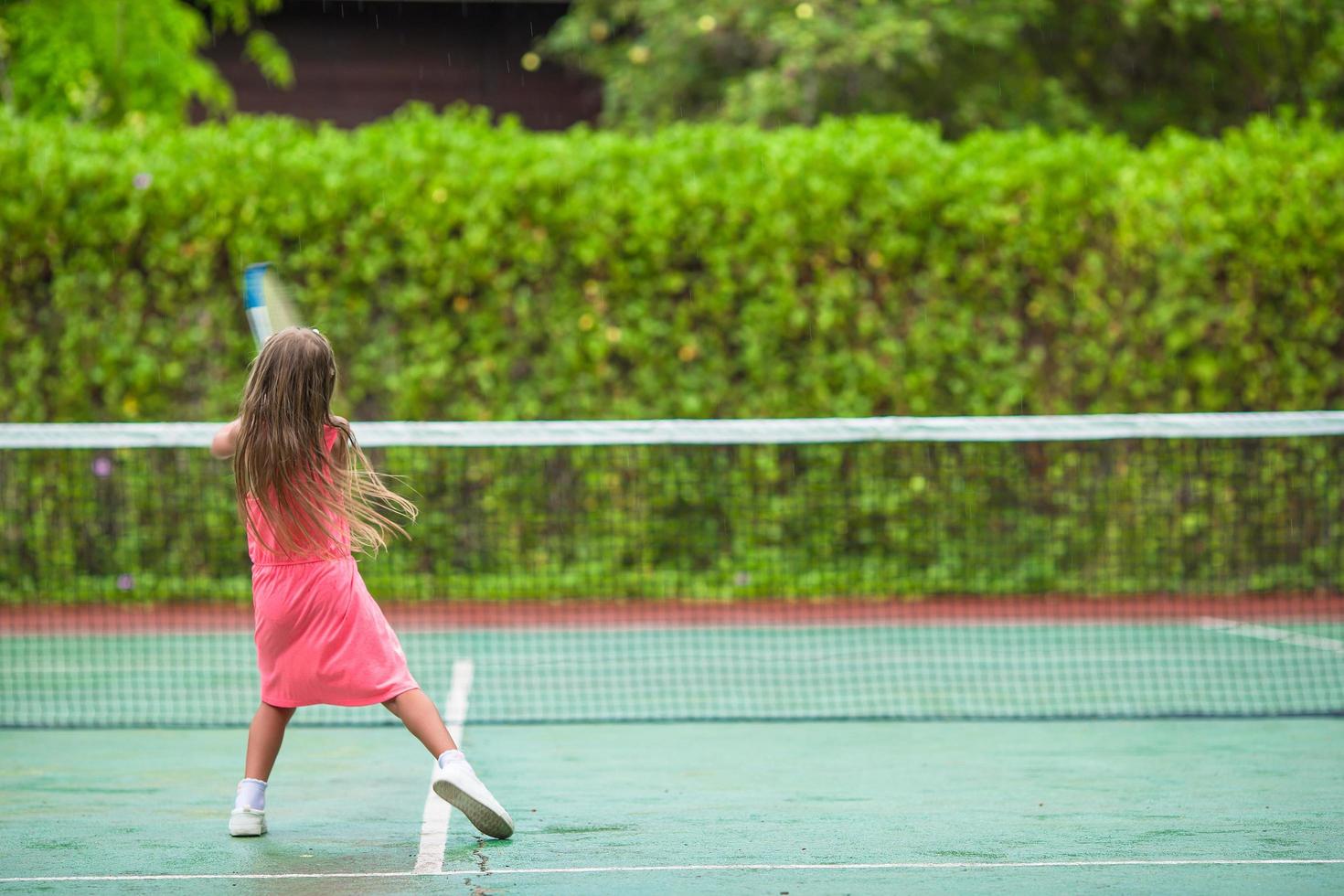 niña jugando tenis en una cancha foto