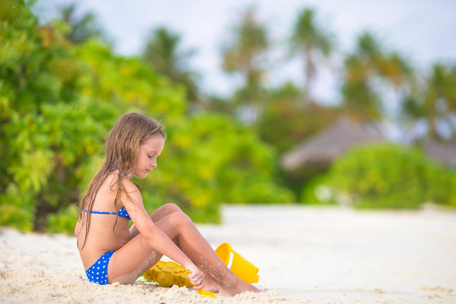 niña jugando en la arena de la playa foto