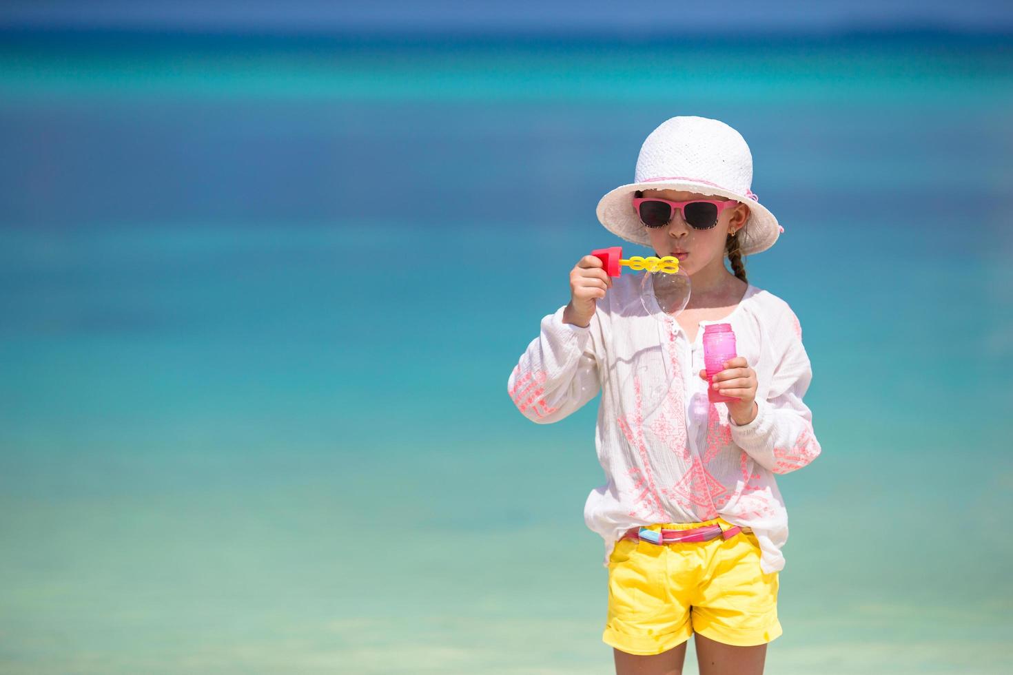 Girl blowing bubbles at a beach photo