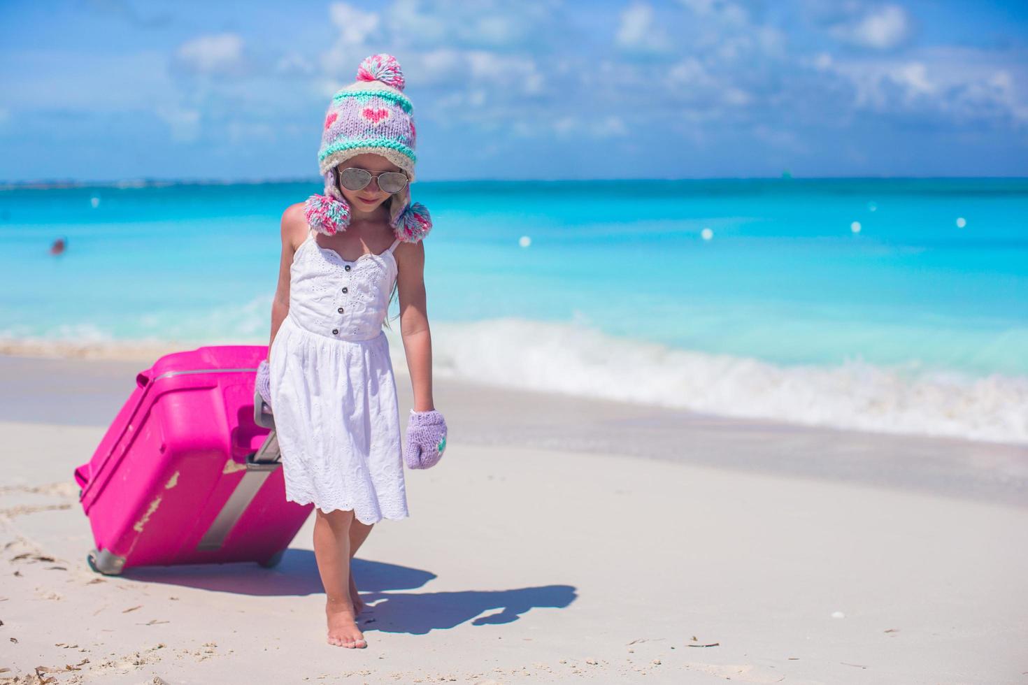 niña, llevando, gorro de invierno, y, mitones, ambulante, con, equipaje, en, un, playa foto