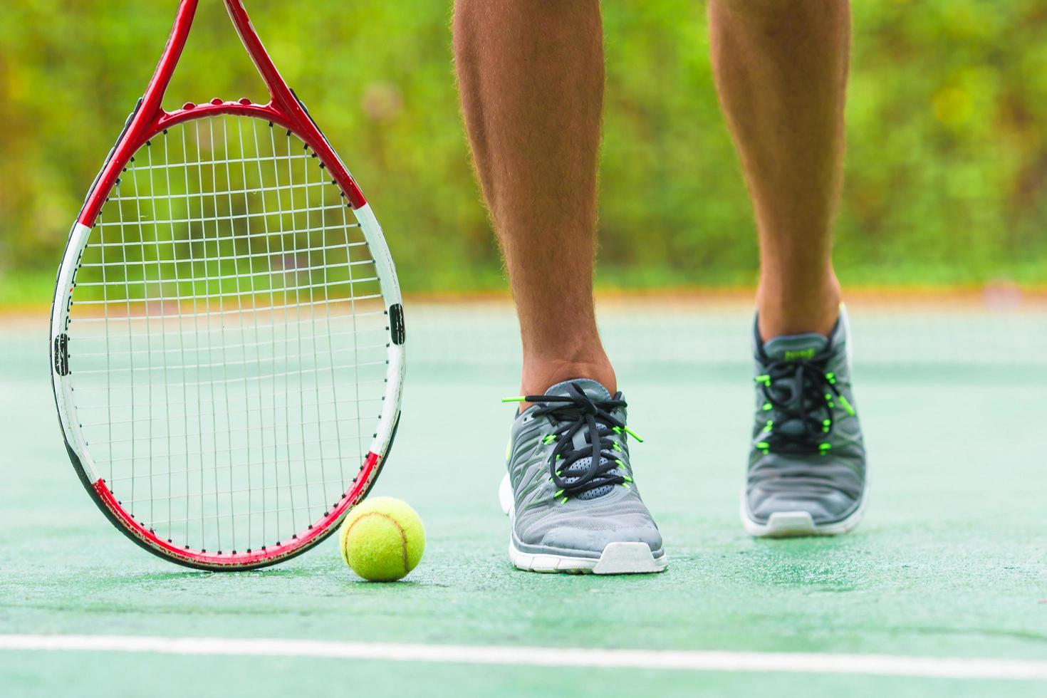 Close-up de zapatillas y una raqueta de tenis y pelota. foto