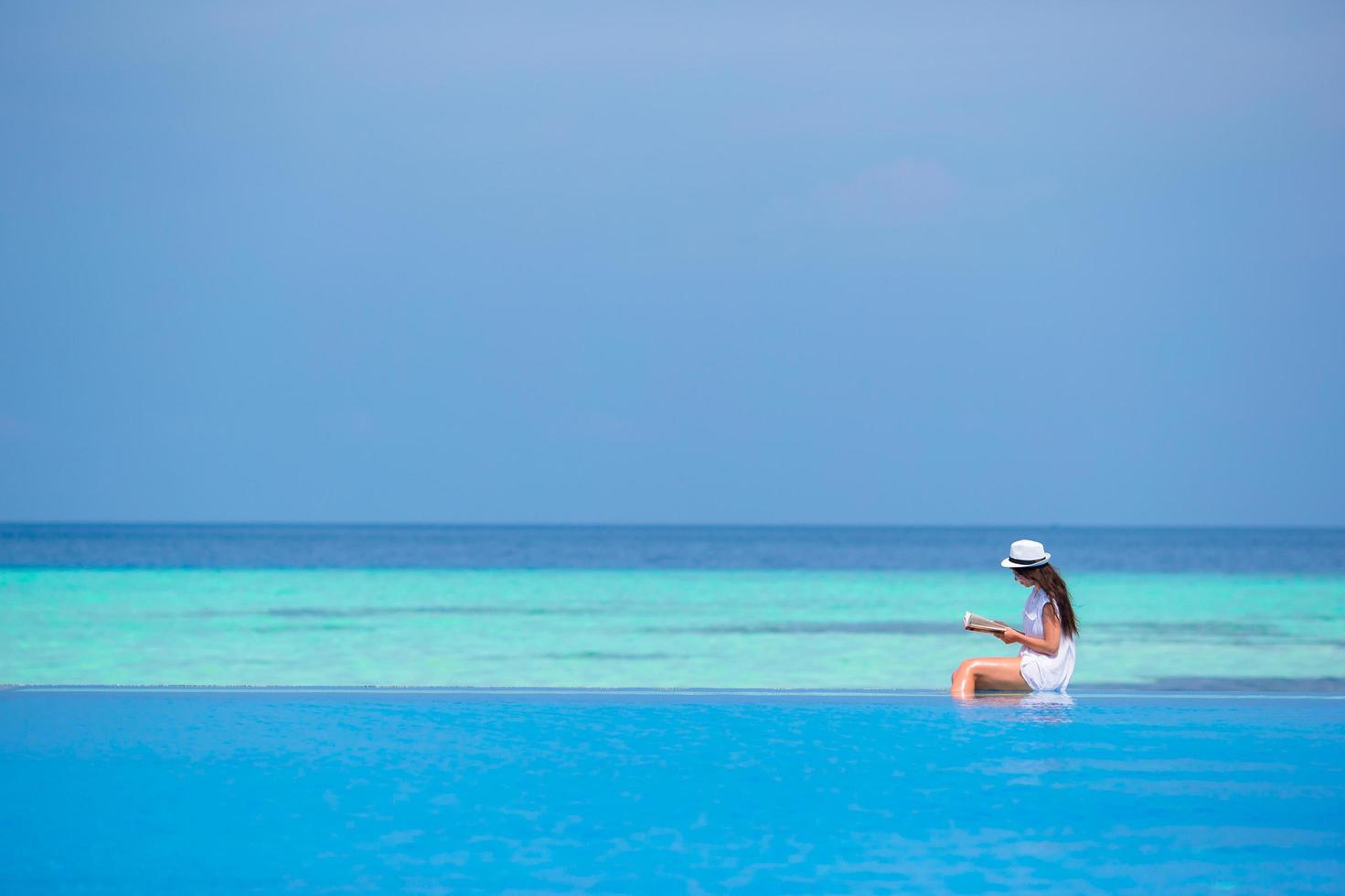 Woman sitting by a pool and reading a book photo