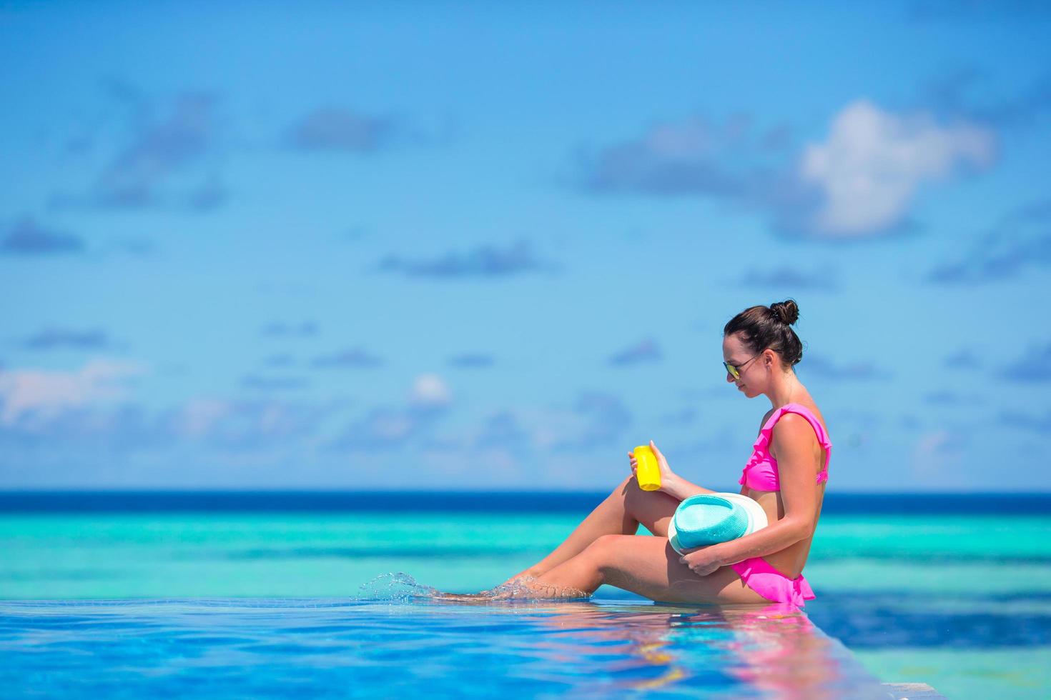 Woman sitting on the edge of a swimming pool photo