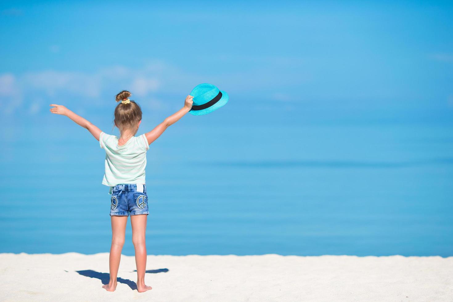 Girl holding hat on beach photo