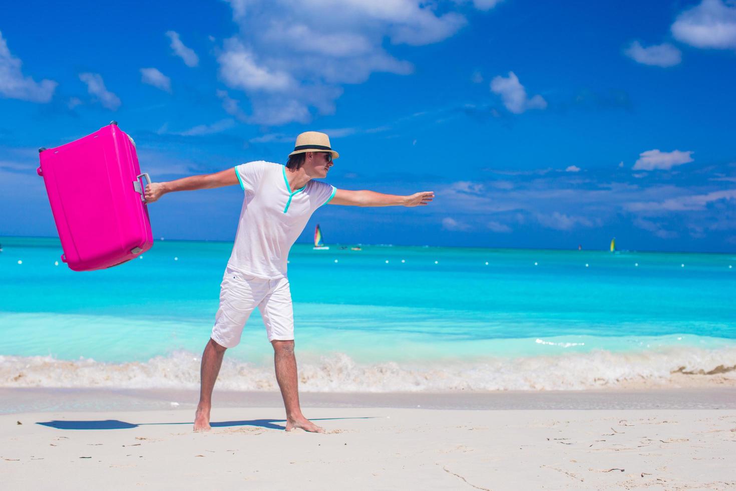 Hombre con equipaje rosa en una playa tropical foto