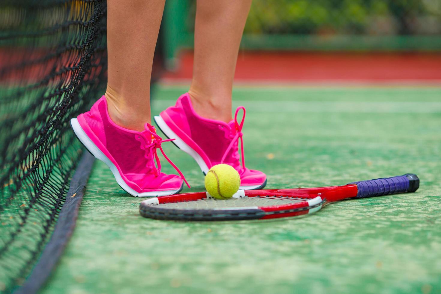 Close-up de zapatillas cerca de la raqueta de tenis y pelota. foto