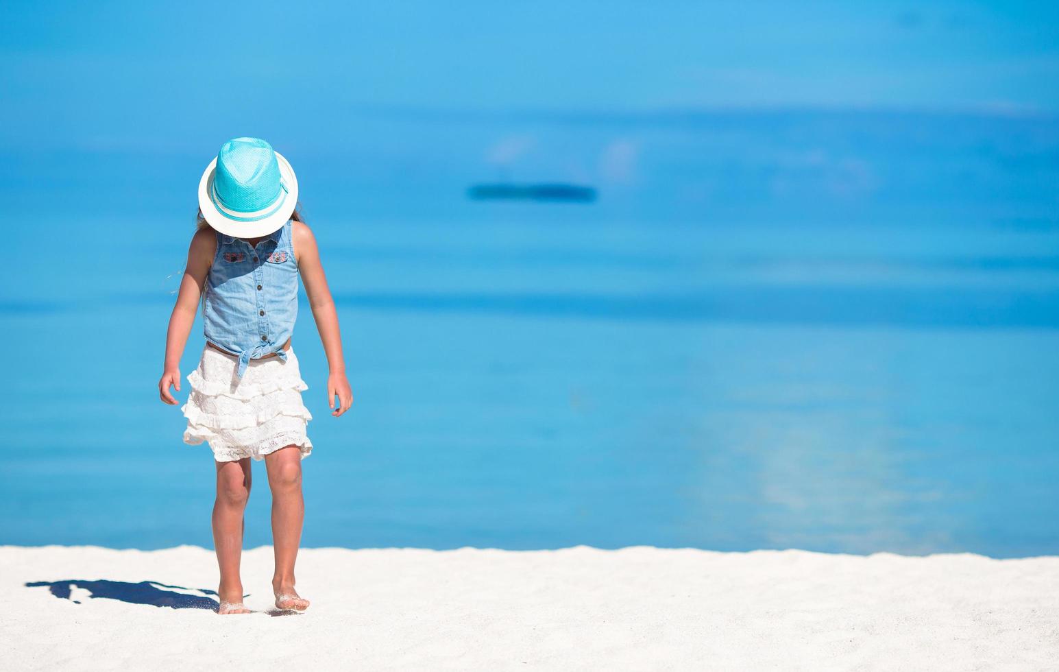 chica con sombrero en una playa de arena blanca foto