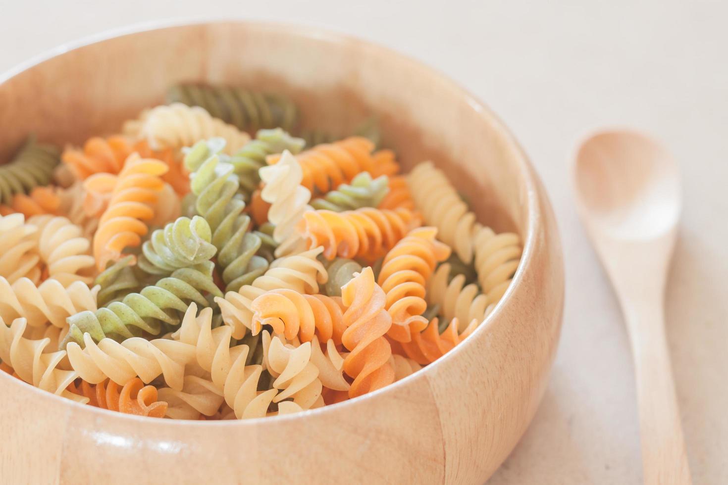 Raw fusilli pasta in a wooden bowl photo