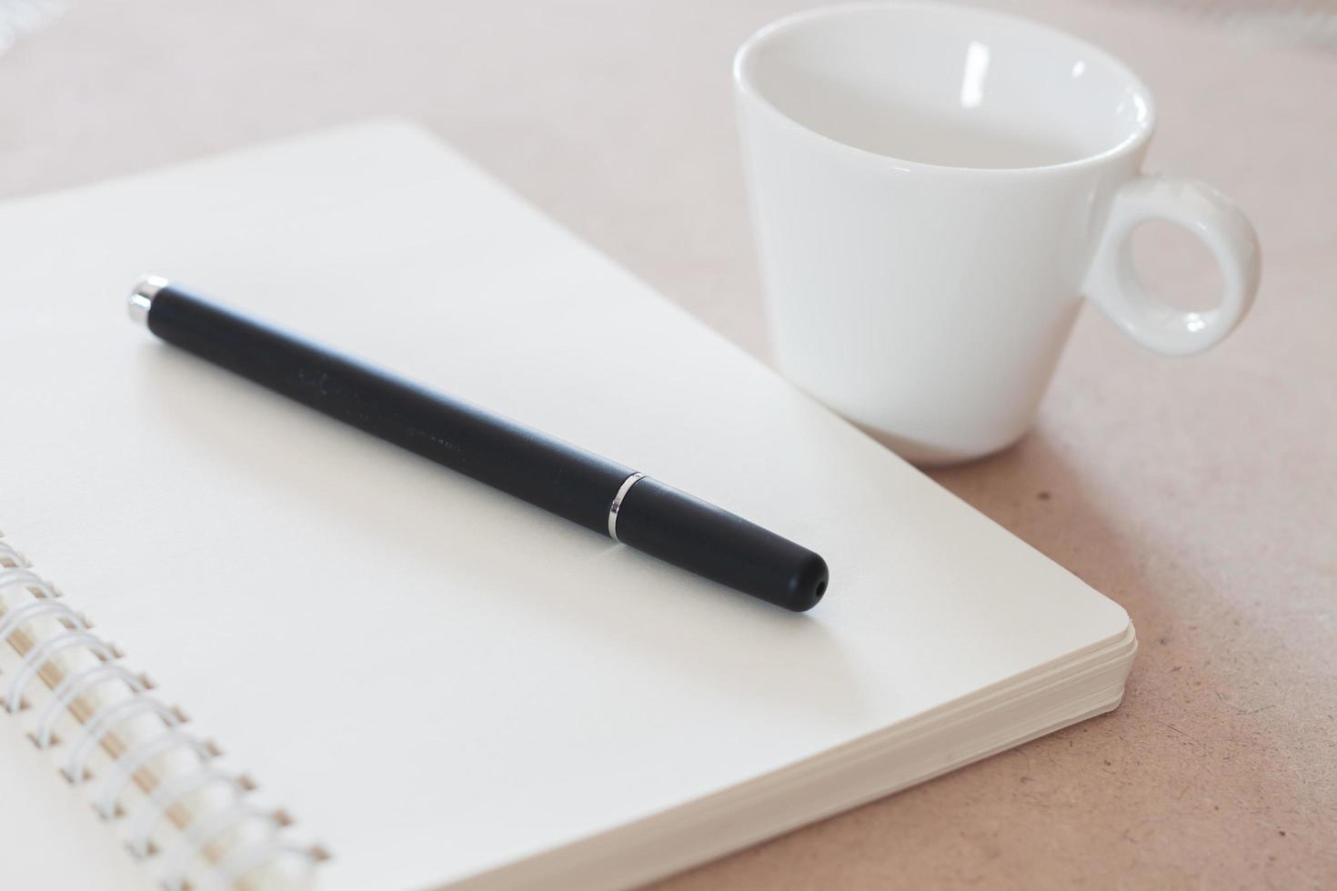 Pen and notebook with a white coffee cup photo