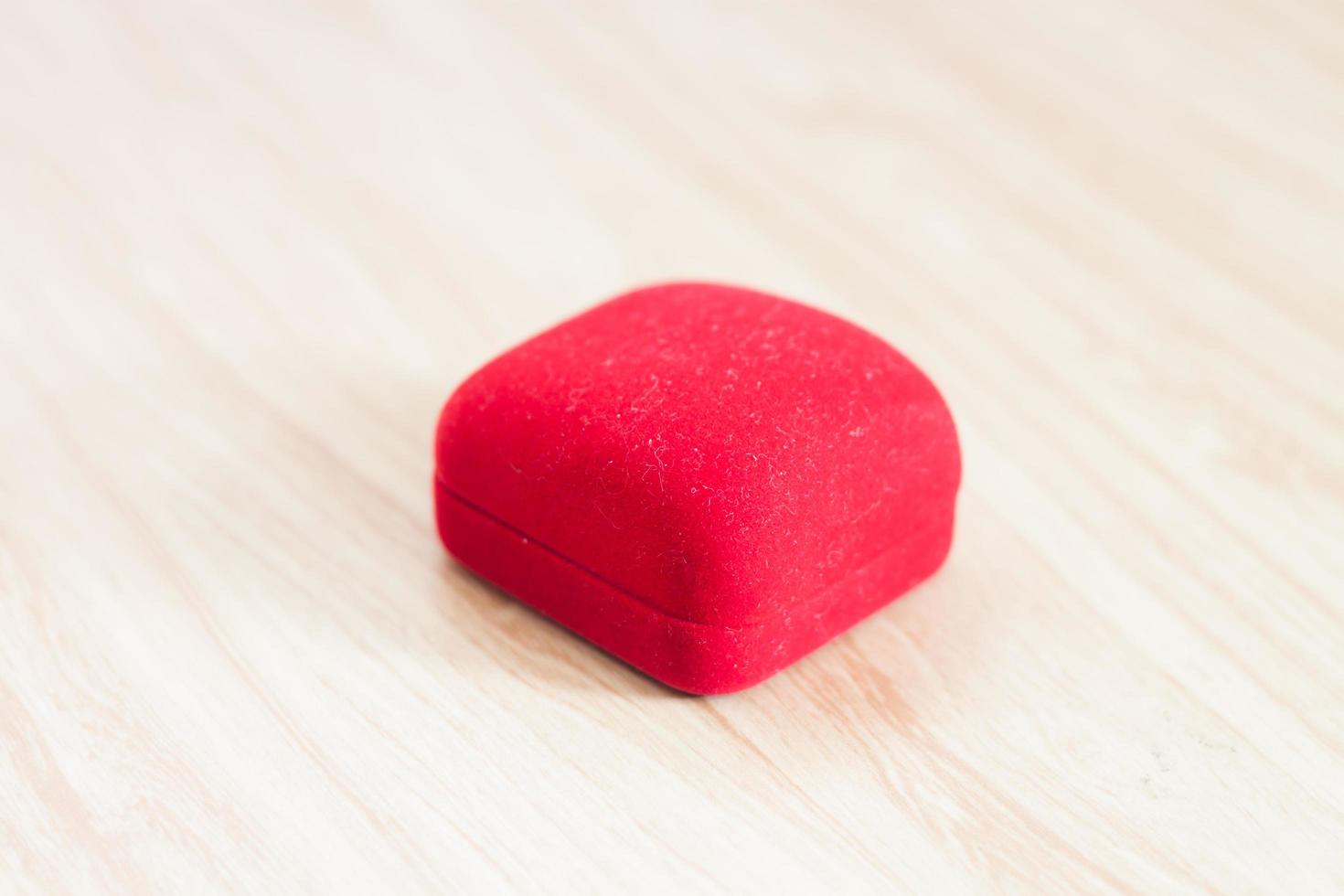 Caja de anillo rojo sobre una mesa de madera foto