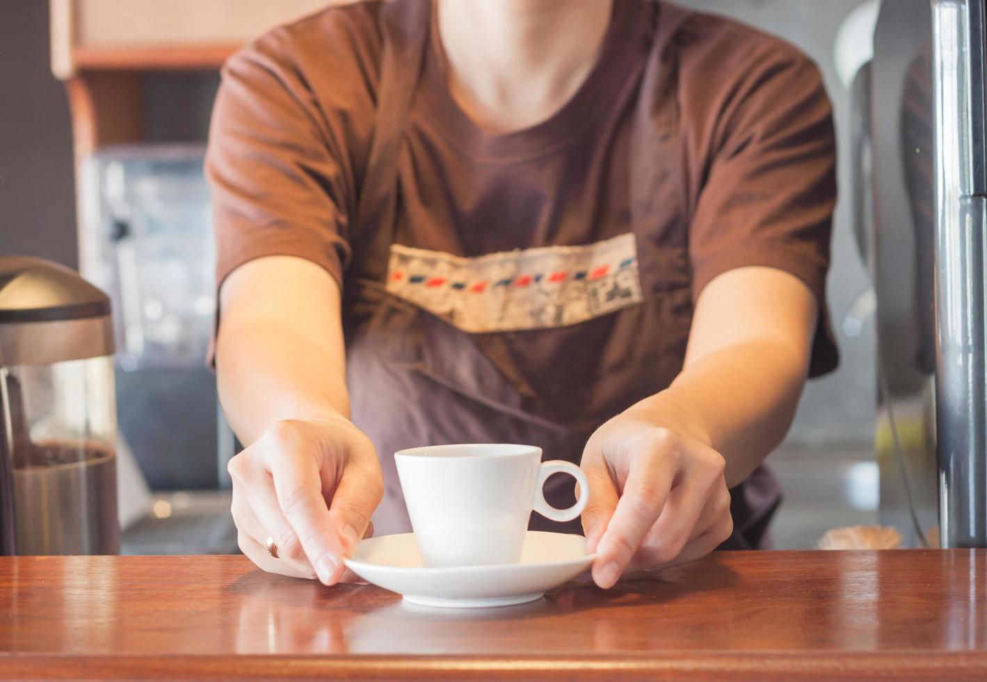 Barista offering a white cup of coffee photo