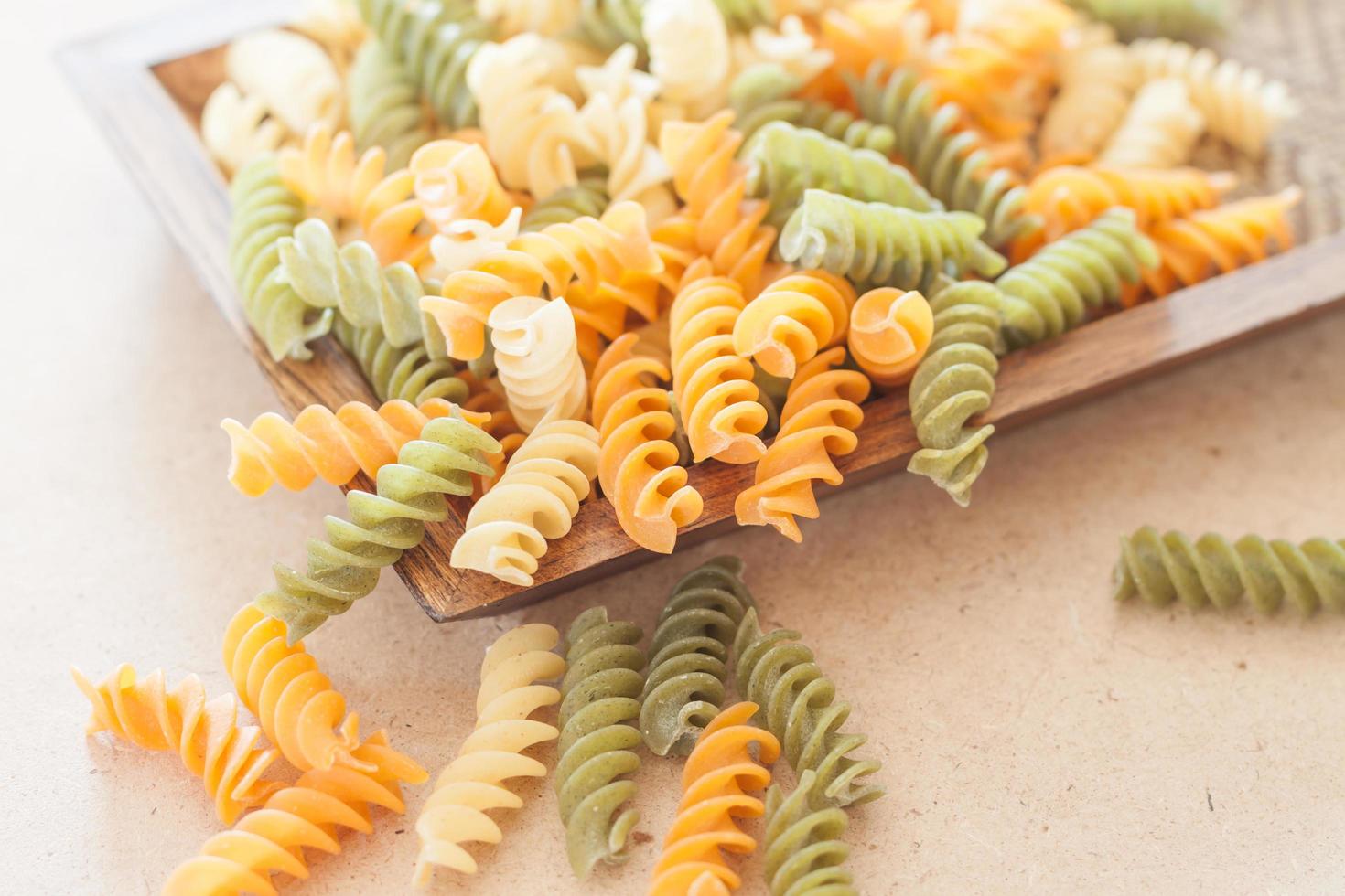 Pasta fusilli cruda en una bandeja de madera foto