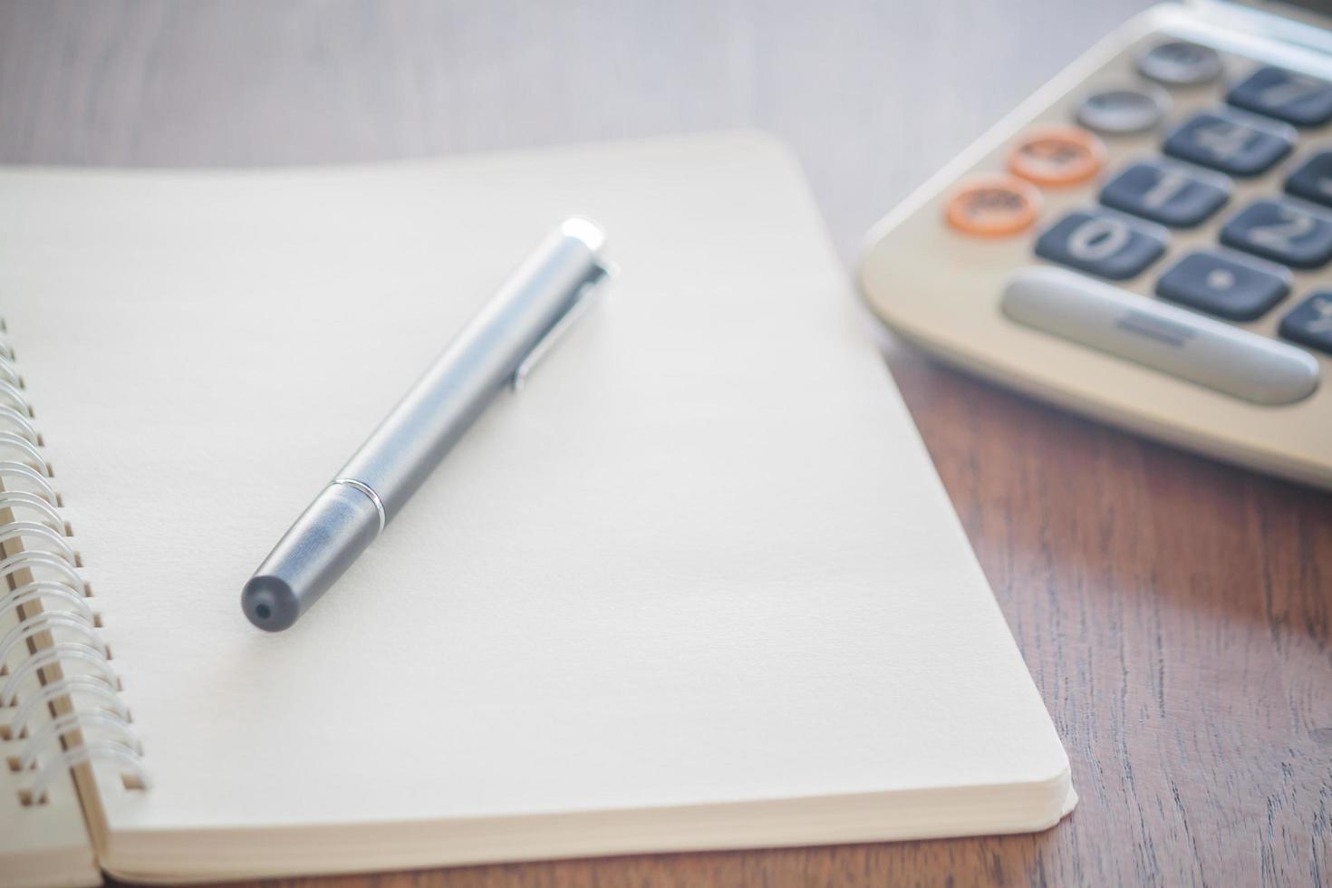 Notebook with a pen on it and a calculator photo