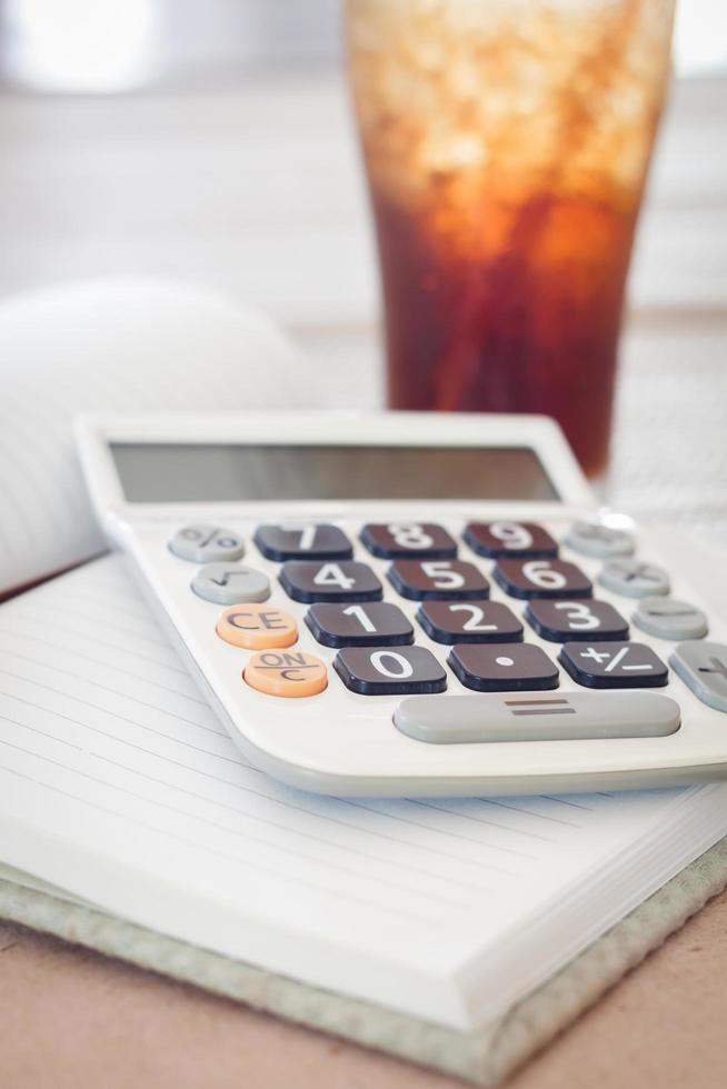 Calculator on a notebook with a glass of cola photo