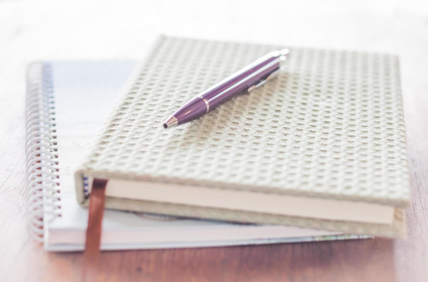 Pen and two notebooks on a wooden table photo