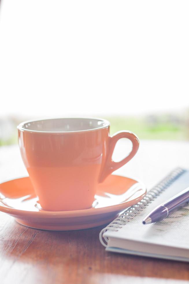 taza de café con un bolígrafo y un cuaderno foto