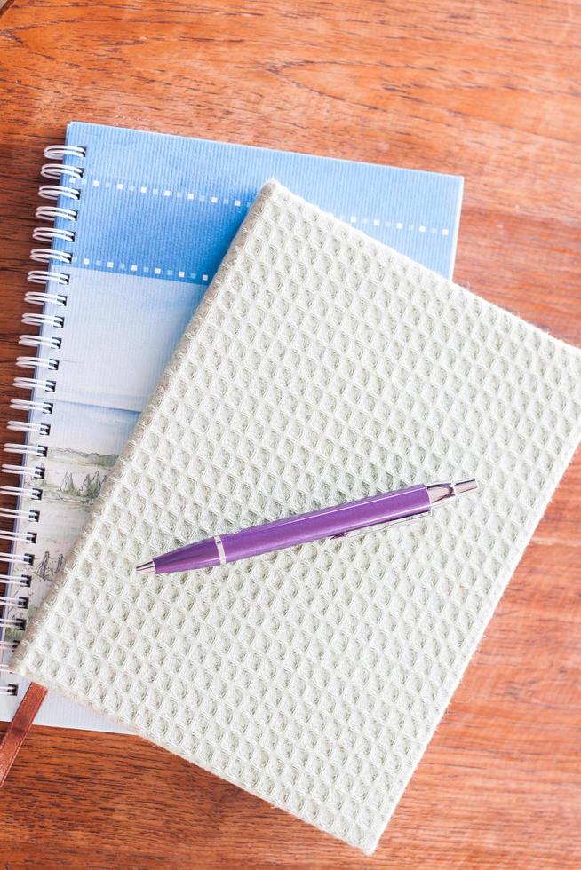 bolígrafo y dos cuadernos en una mesa de madera foto