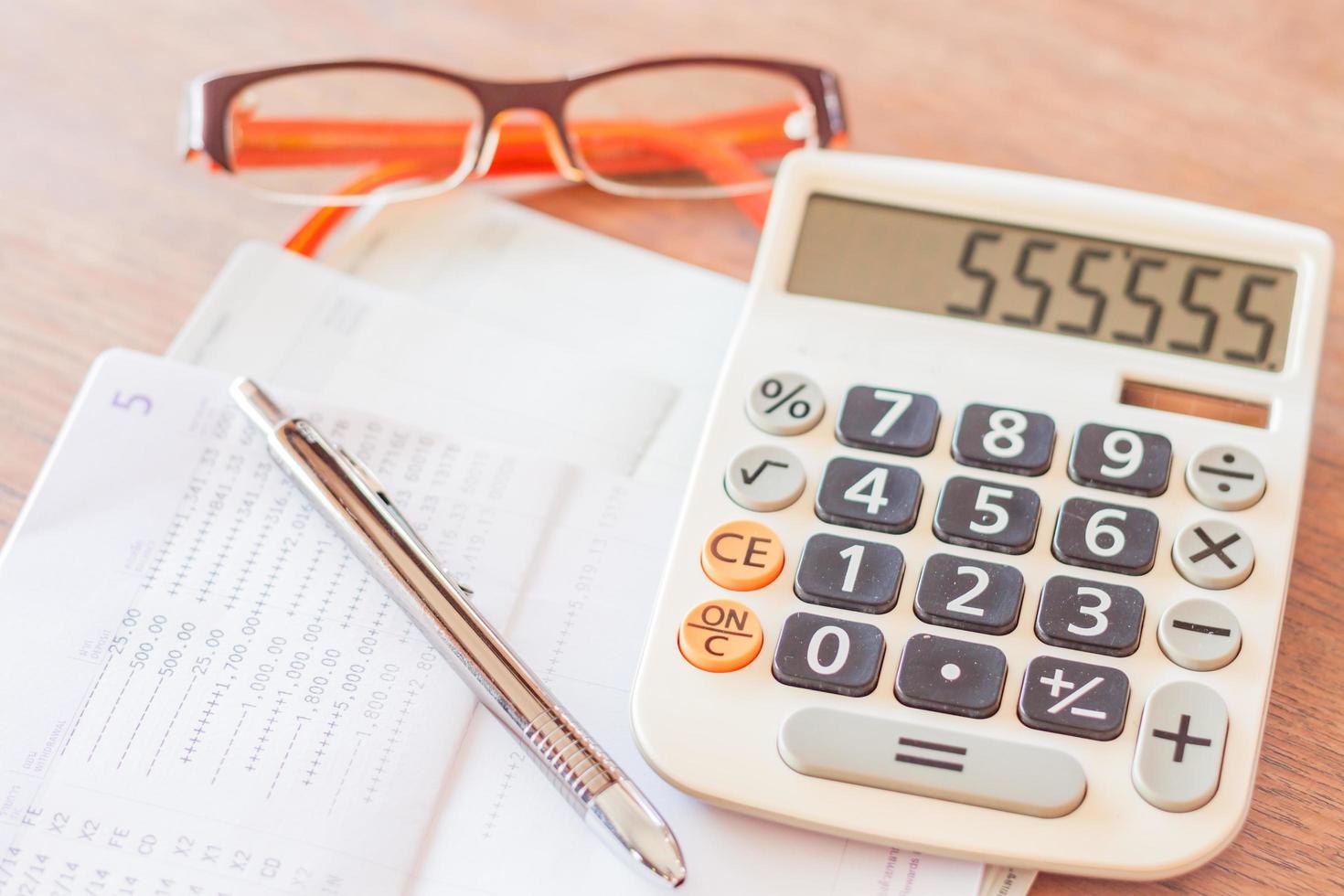 Workstation with a calculator, pen, and eyeglasses photo