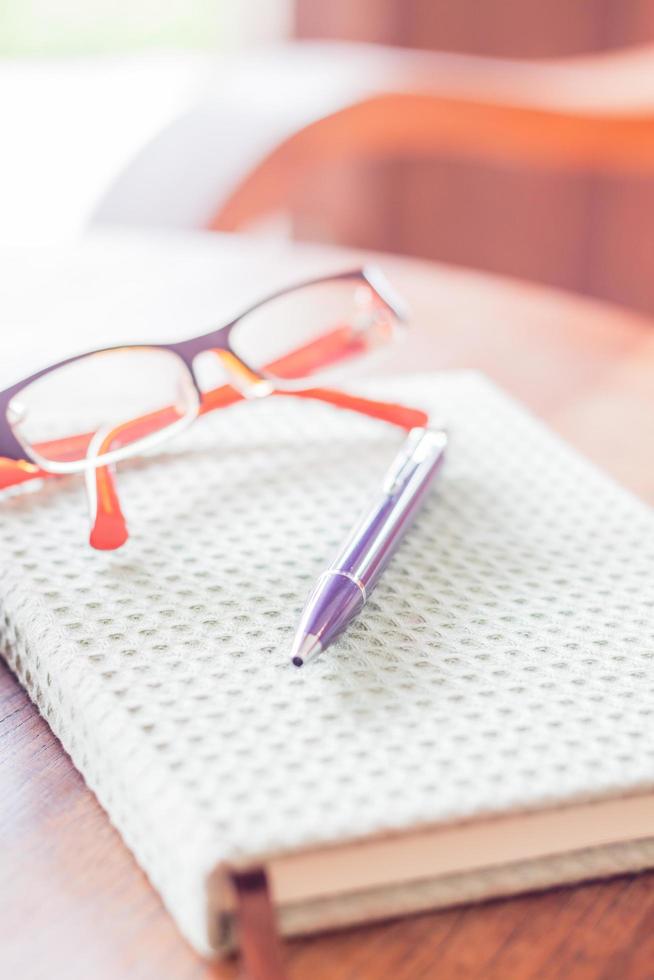 lápiz y anteojos en un cuaderno sobre una mesa foto