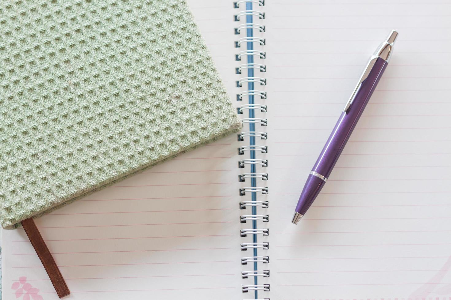 vista superior de un cuaderno verde, un bolígrafo y un cuaderno de espiral foto