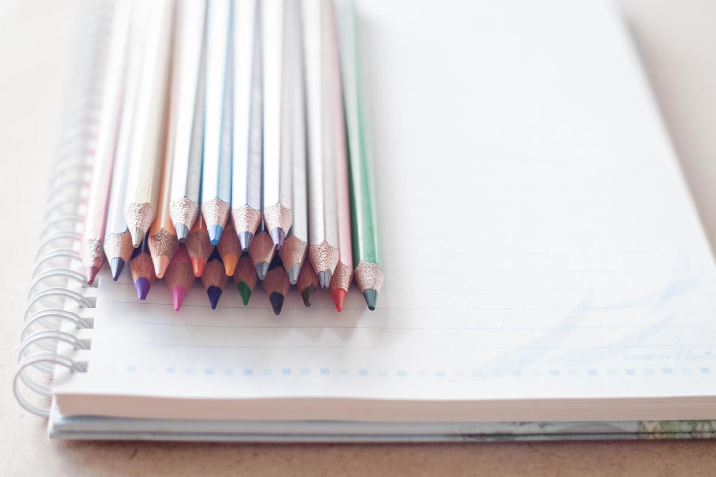 Stack of colorful pencils on a spiral notebook photo