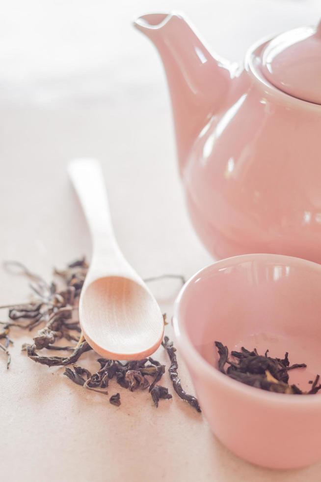 té seco y una cuchara de madera con una jarra de cerámica foto