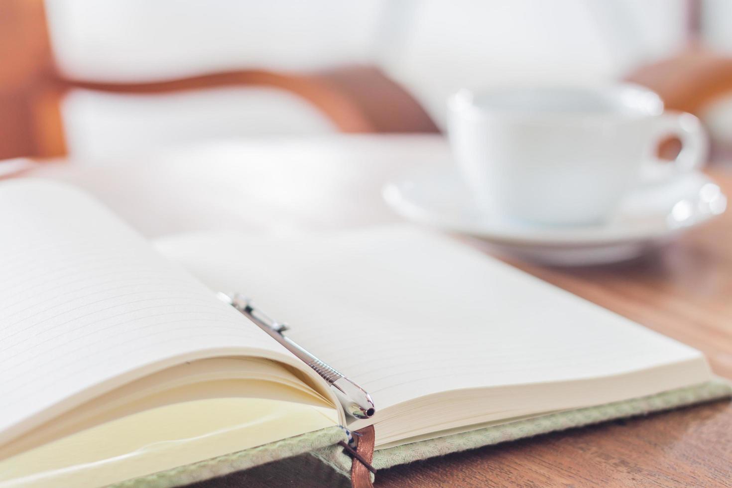 cuaderno abierto y bolígrafo con una taza de café foto