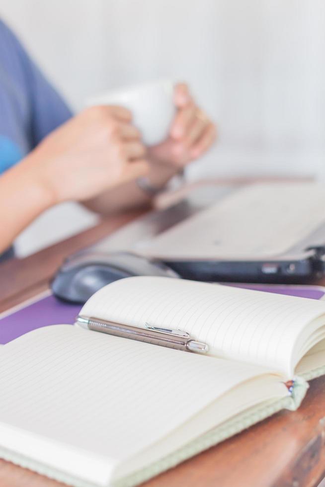 cuaderno y bolígrafo con una persona de fondo. foto