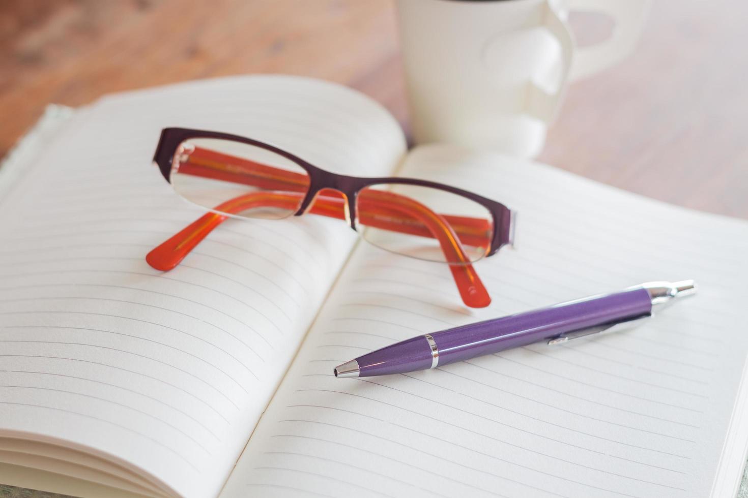 Pen and reading glasses on a notebook photo