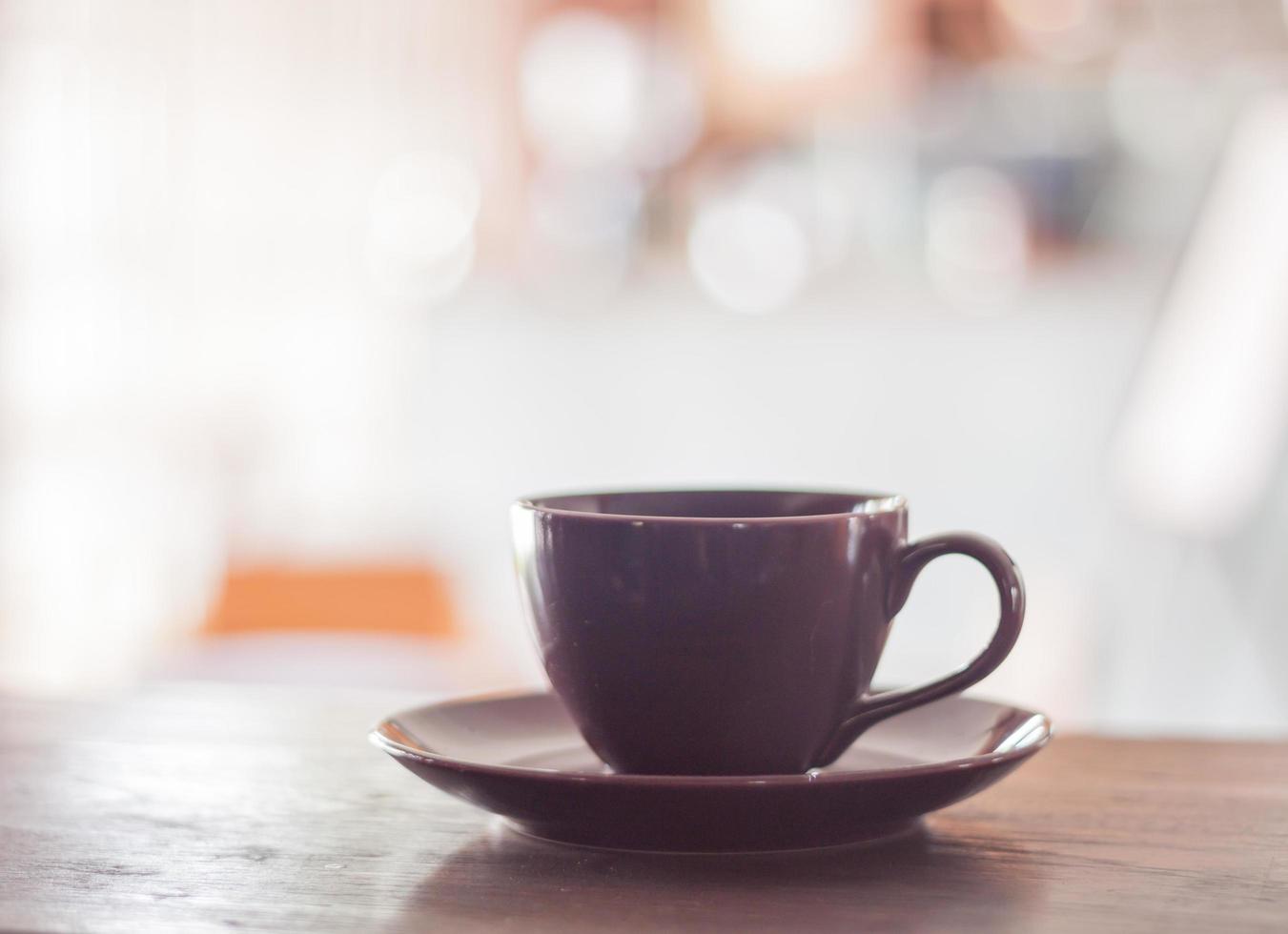 Taza de café púrpura sobre una mesa de madera foto