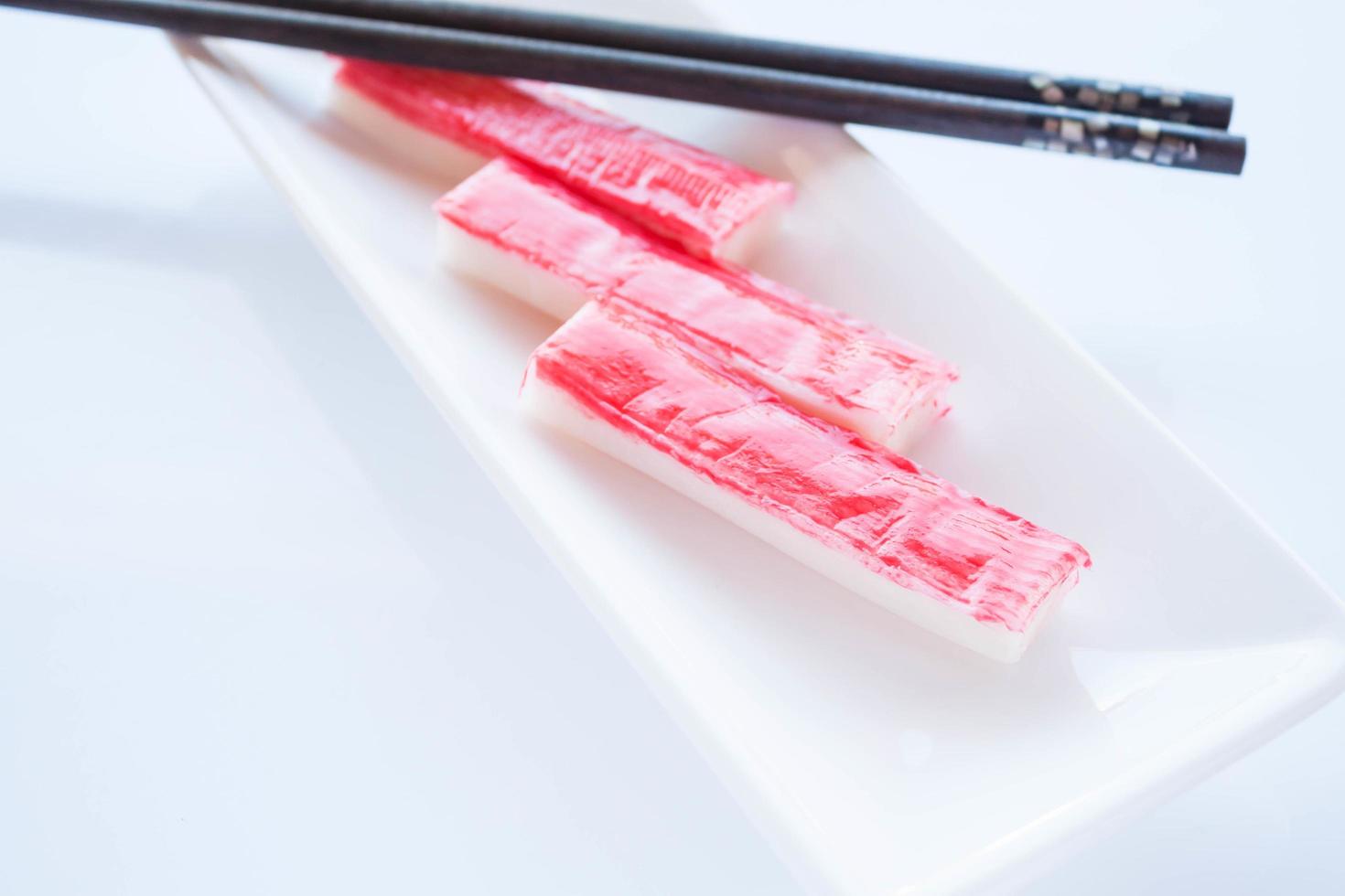 Crab sticks with chopsticks on a white plate photo