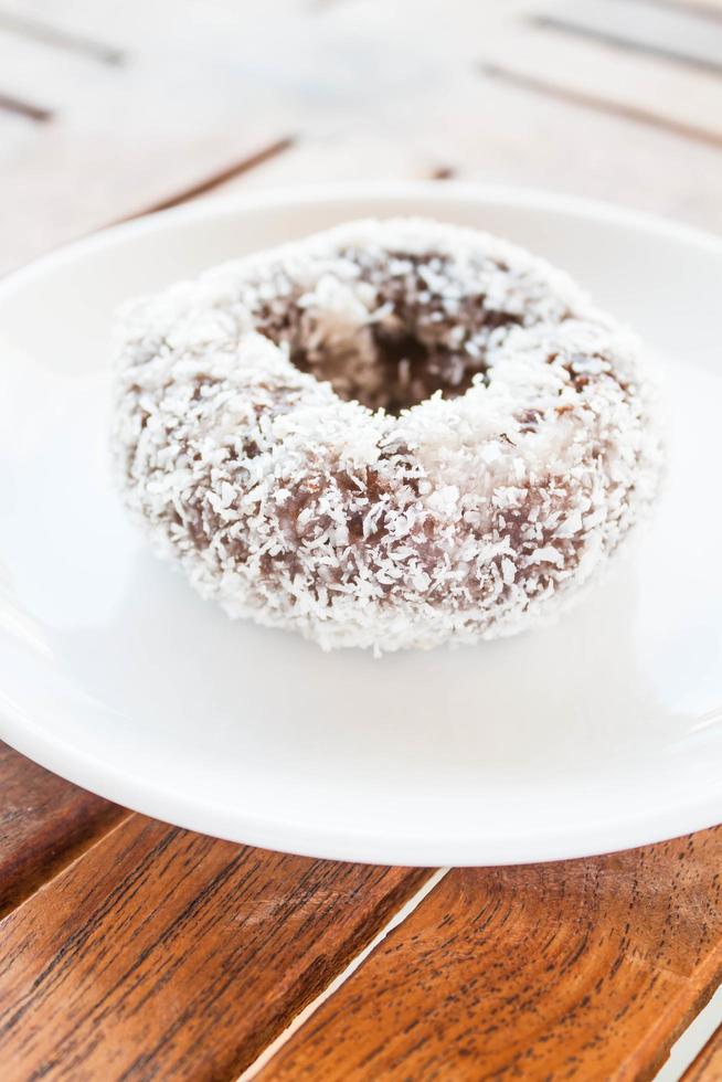 Donut de chocolate con coco en una placa blanca. foto