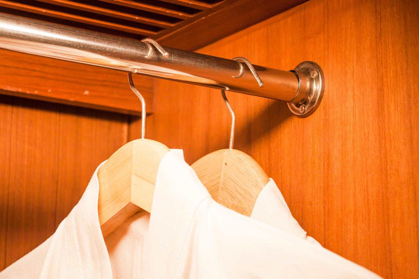 White bathrobes hanging on wooded hangers photo