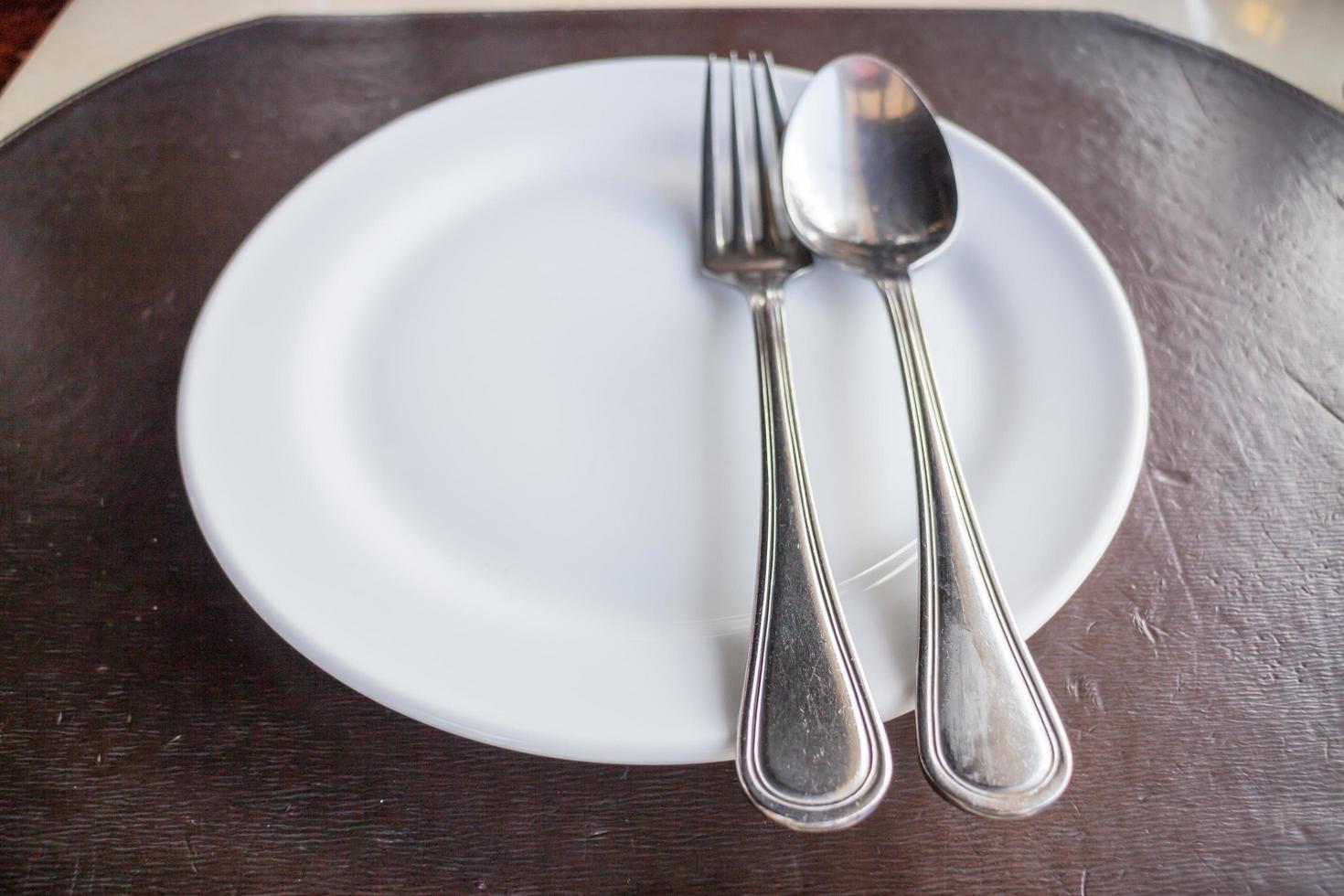 Vista superior de un plato blanco con una cuchara y un tenedor. foto