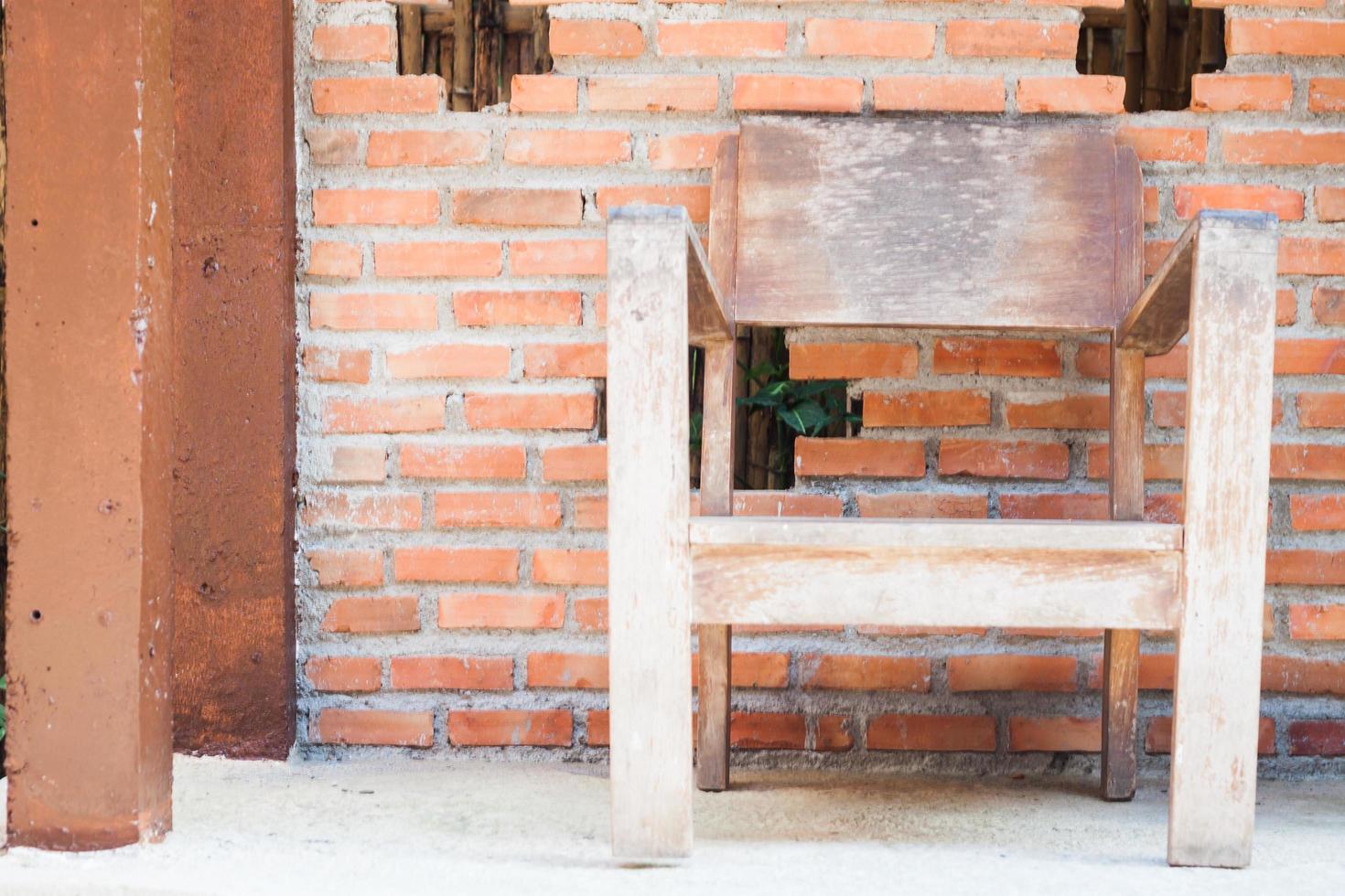 silla de madera con una pared de ladrillo rojo foto