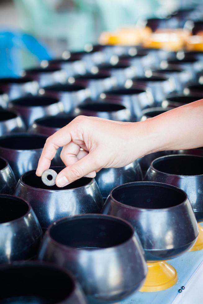 Woman putting a coin in an alms-bowl for merit photo