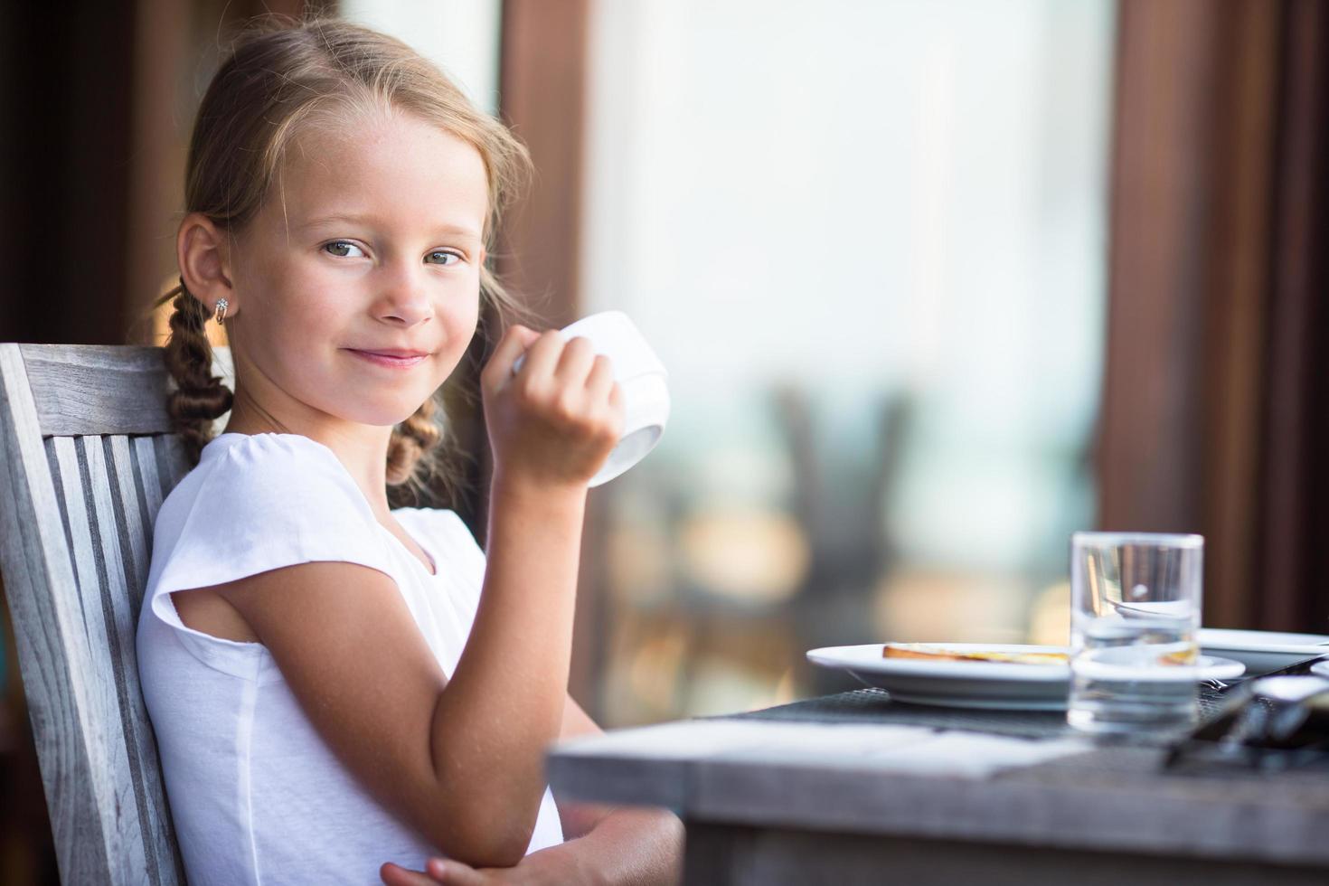 niña bebiendo té en la mesa foto