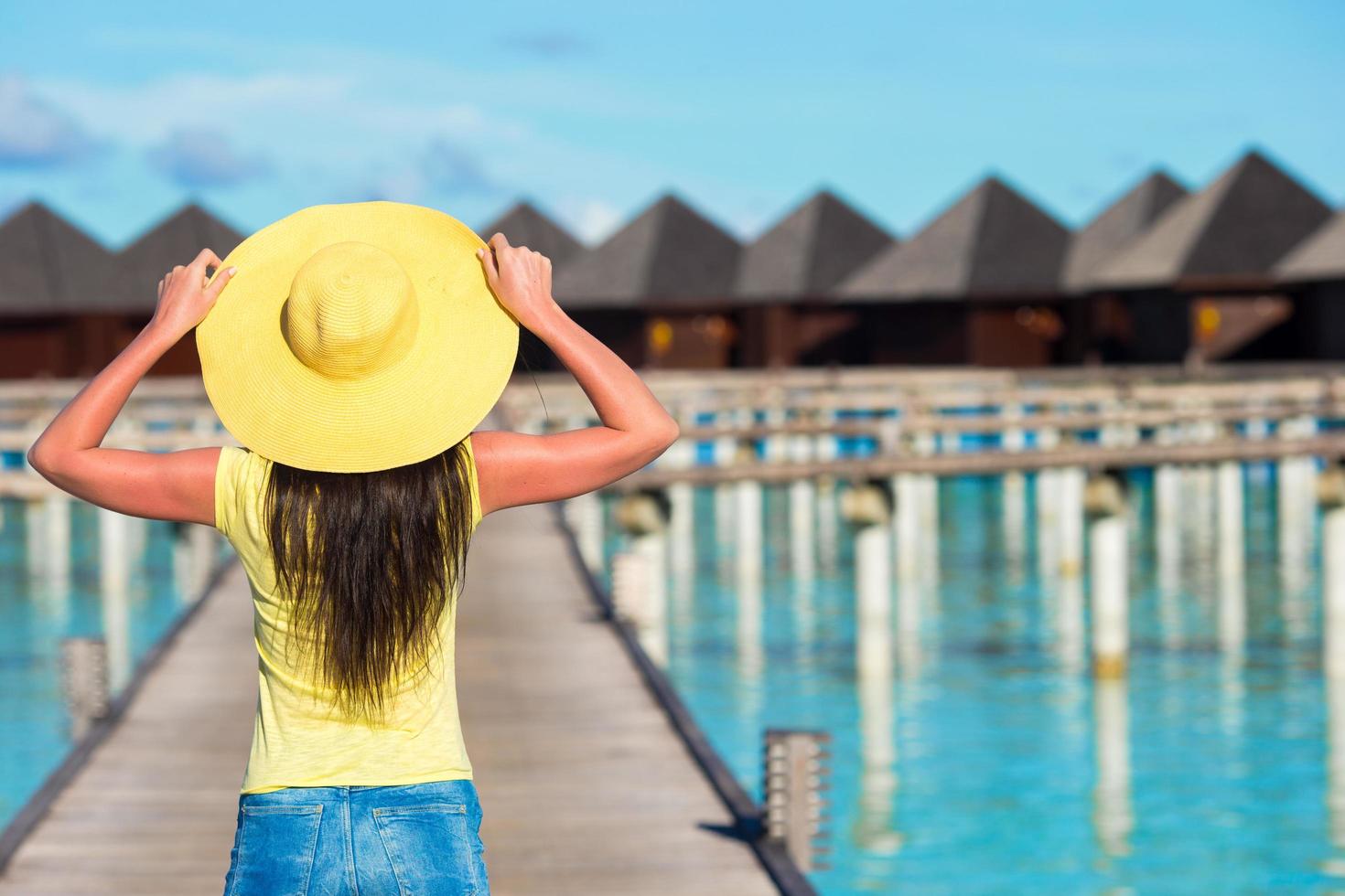 Maldives, South Asia, 2020 - A woman walking on a dock near a resort on the ocean photo