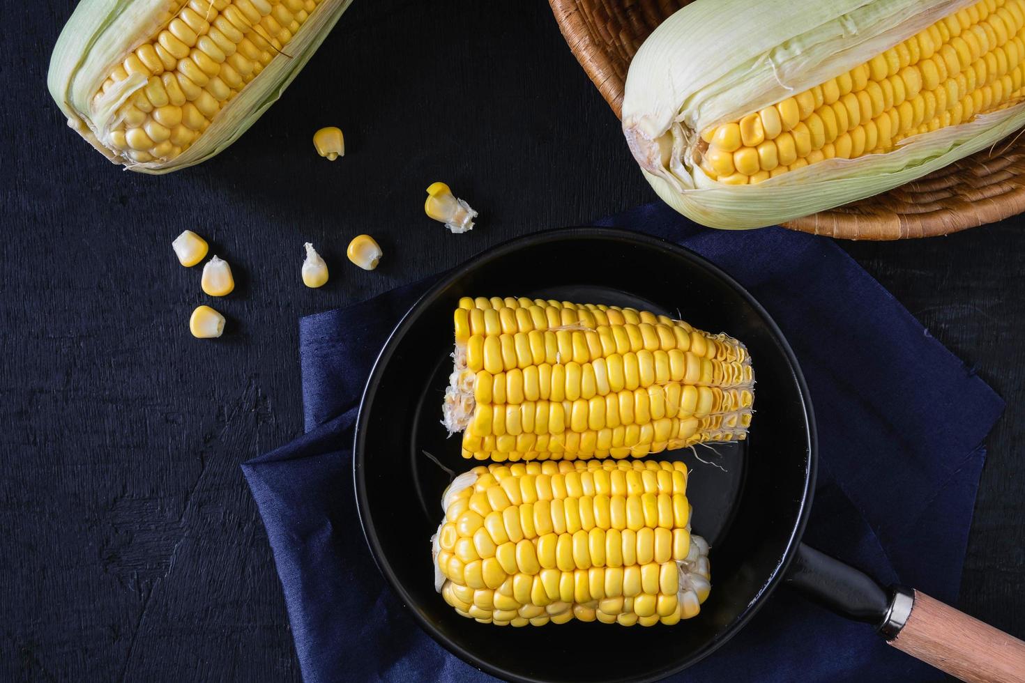 Raw fresh corn in pan on black background photo