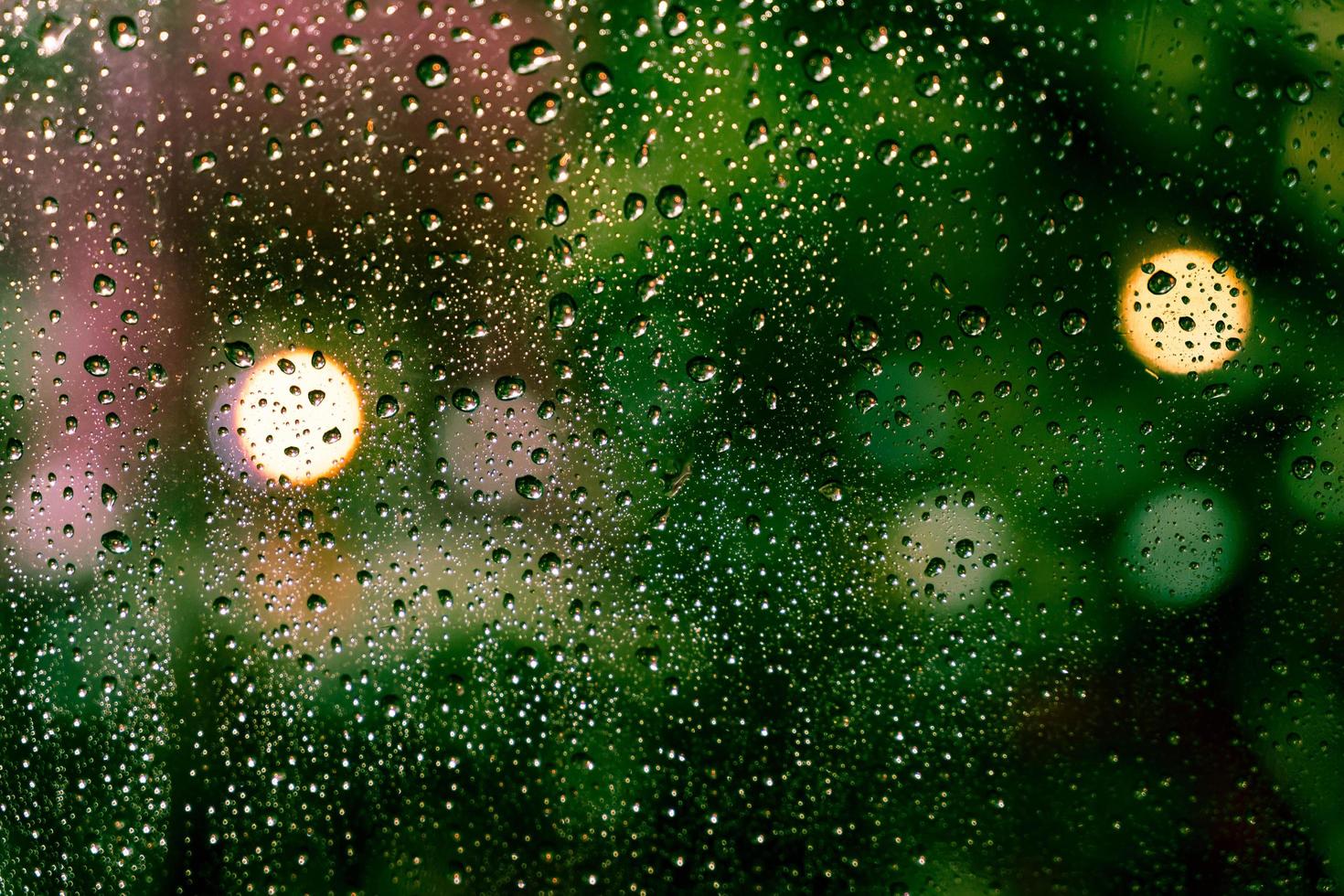 Rain drops on the window with colorful bokeh photo