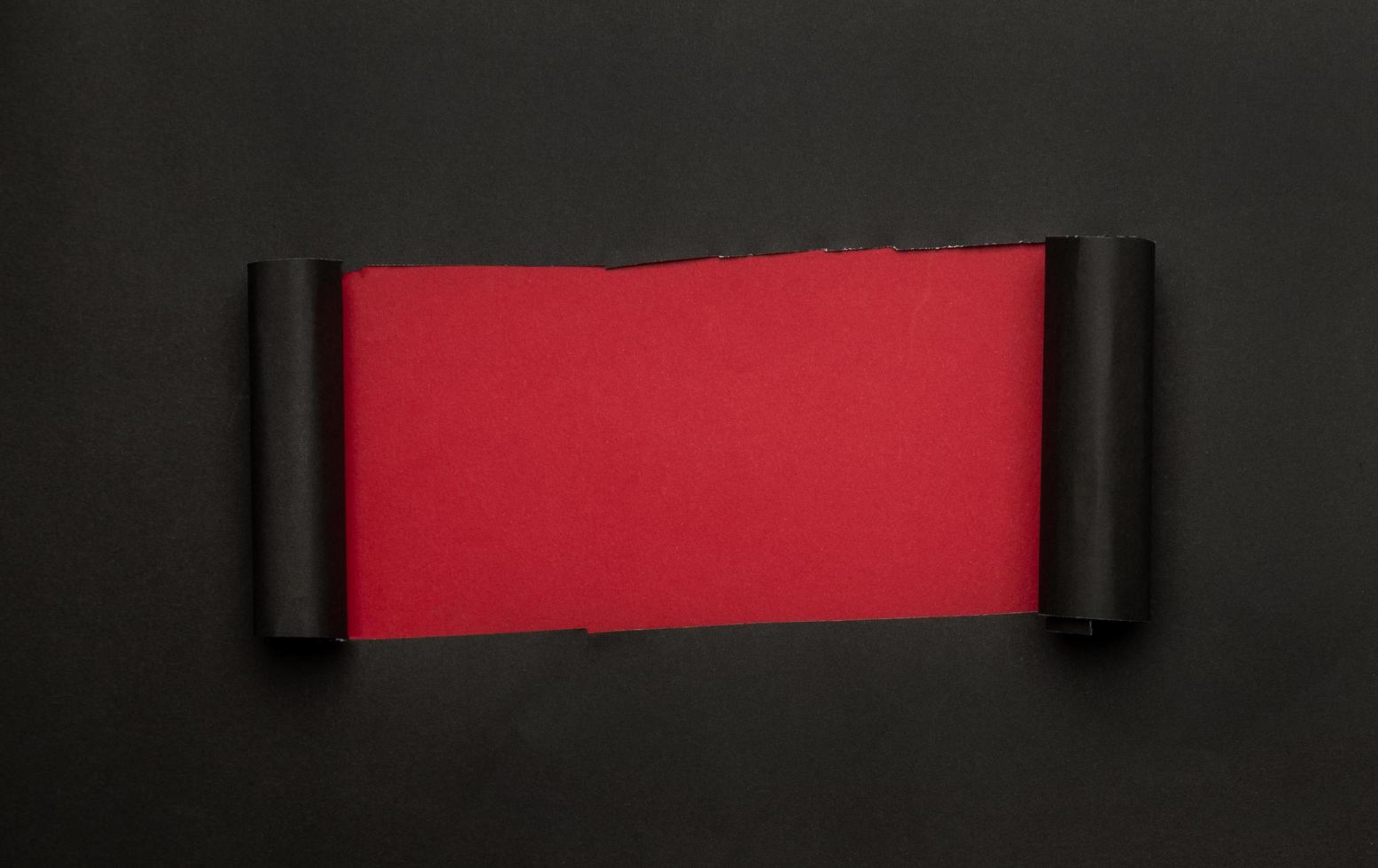 Black torn paper on red background photo