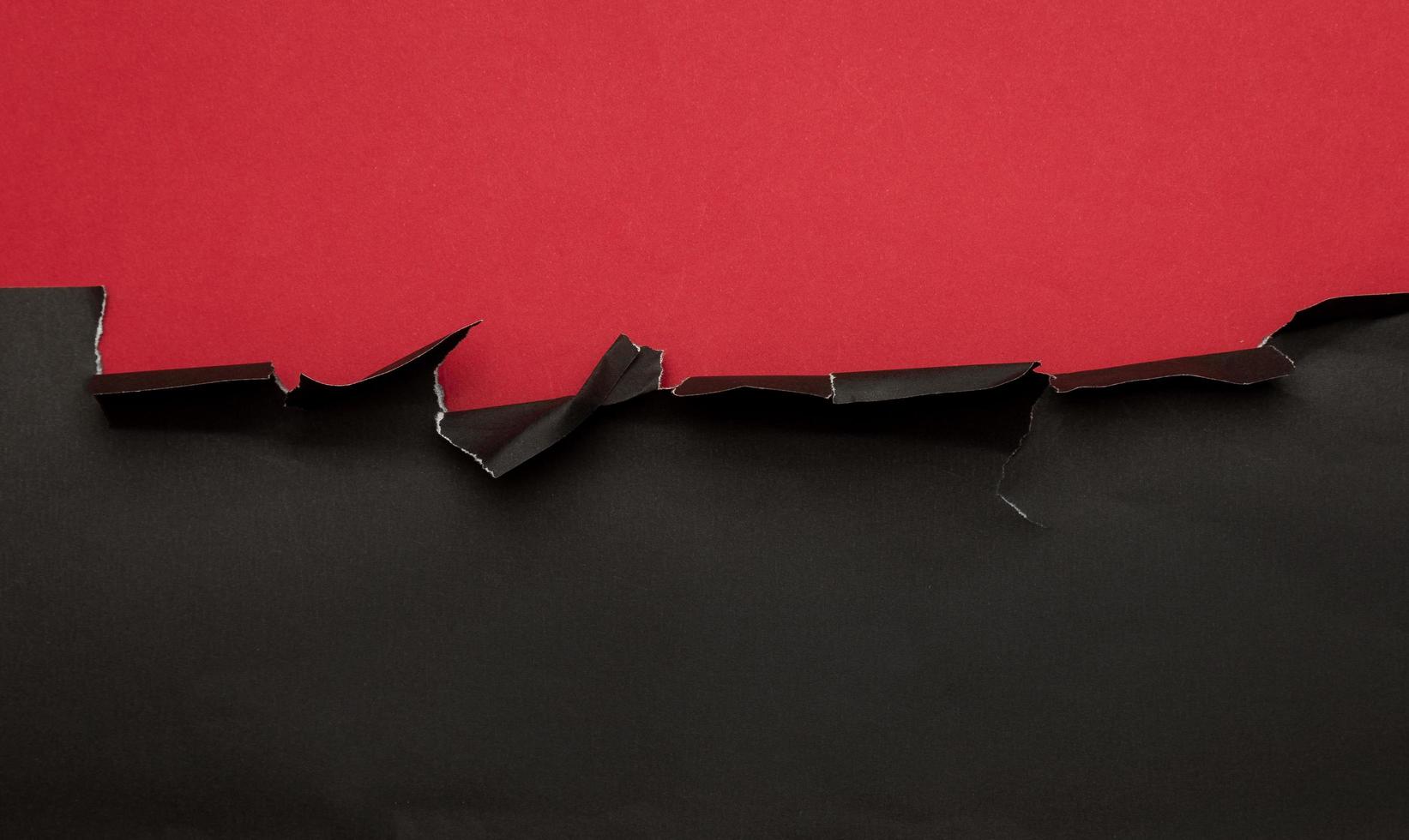 Black torn paper on red background photo