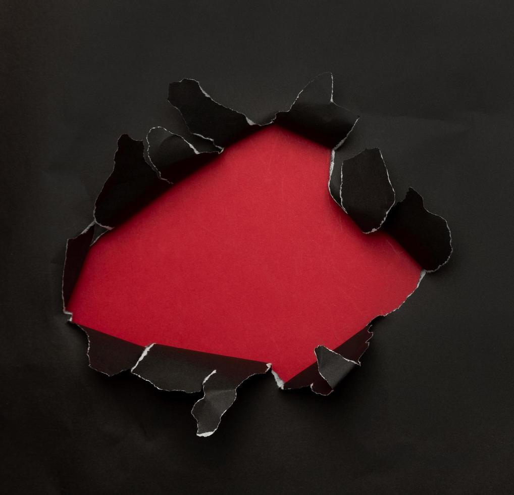 Black torn paper on red background photo