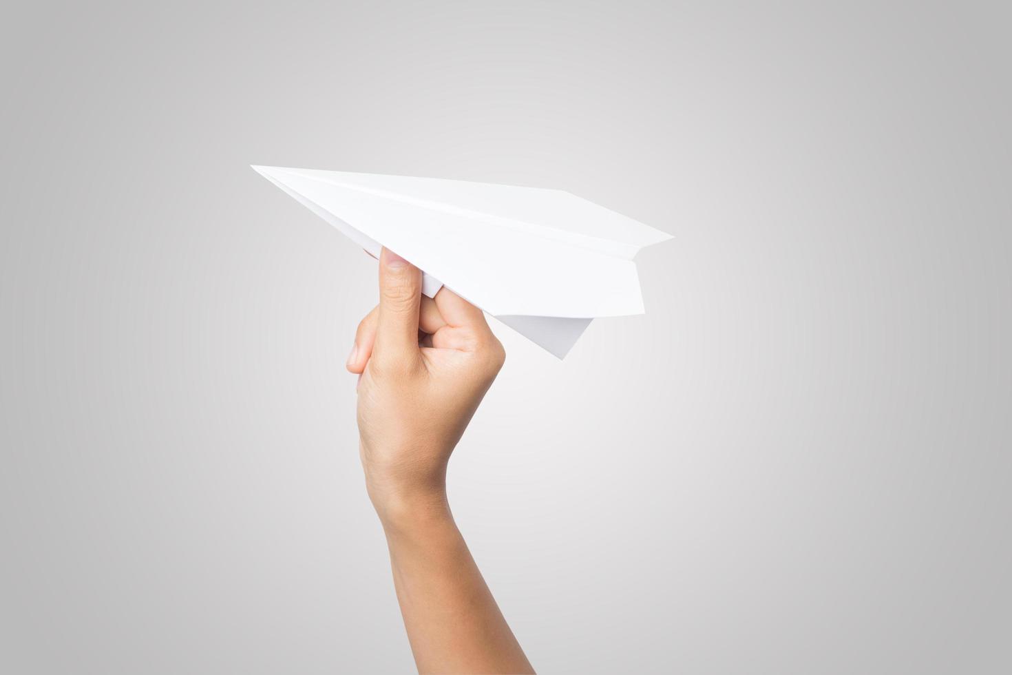 A woman's hand holds a paper airplane on white background photo